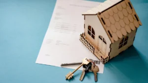 Maquette de maison en bois avec clés posées sur un formulaire d'attestation de loyer pour demande d'aide au logement CAF