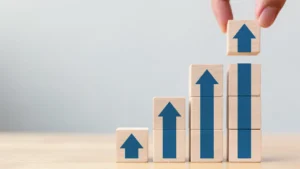Blocs en bois empilés avec des flèches vers le haut illustrant l’augmentation du loyer en 2026, le calcul de la hausse et l’évolution des indices réglementaires.