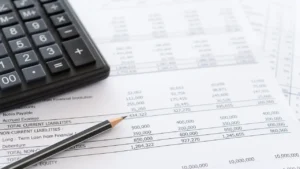 Documents de comptabilité avec calculatrice et tableau de chiffres, illustrant le choix entre le régime micro-BIC et le régime réel pour la comptabilité LMNP en 2026.