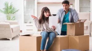 Locataire lisant une lettre de préavis envoyée par le propriétaire, assise parmi des cartons de déménagement, illustrant la procédure de préavis entre propriétaire et locataire en 2026.