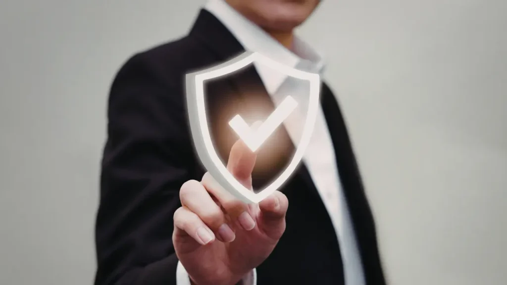 Personne en tenue professionnelle touchant une icône de bouclier avec coche lumineuse, symbole de protection, sécurité et assurance.