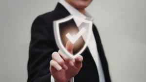 Personne en tenue professionnelle touchant une icône de bouclier avec coche lumineuse, symbole de protection, sécurité et assurance.